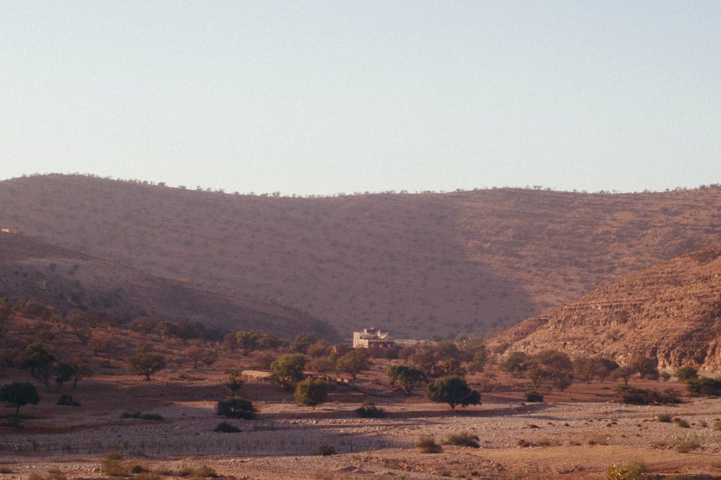 a landscape with a house in the middle of a desert